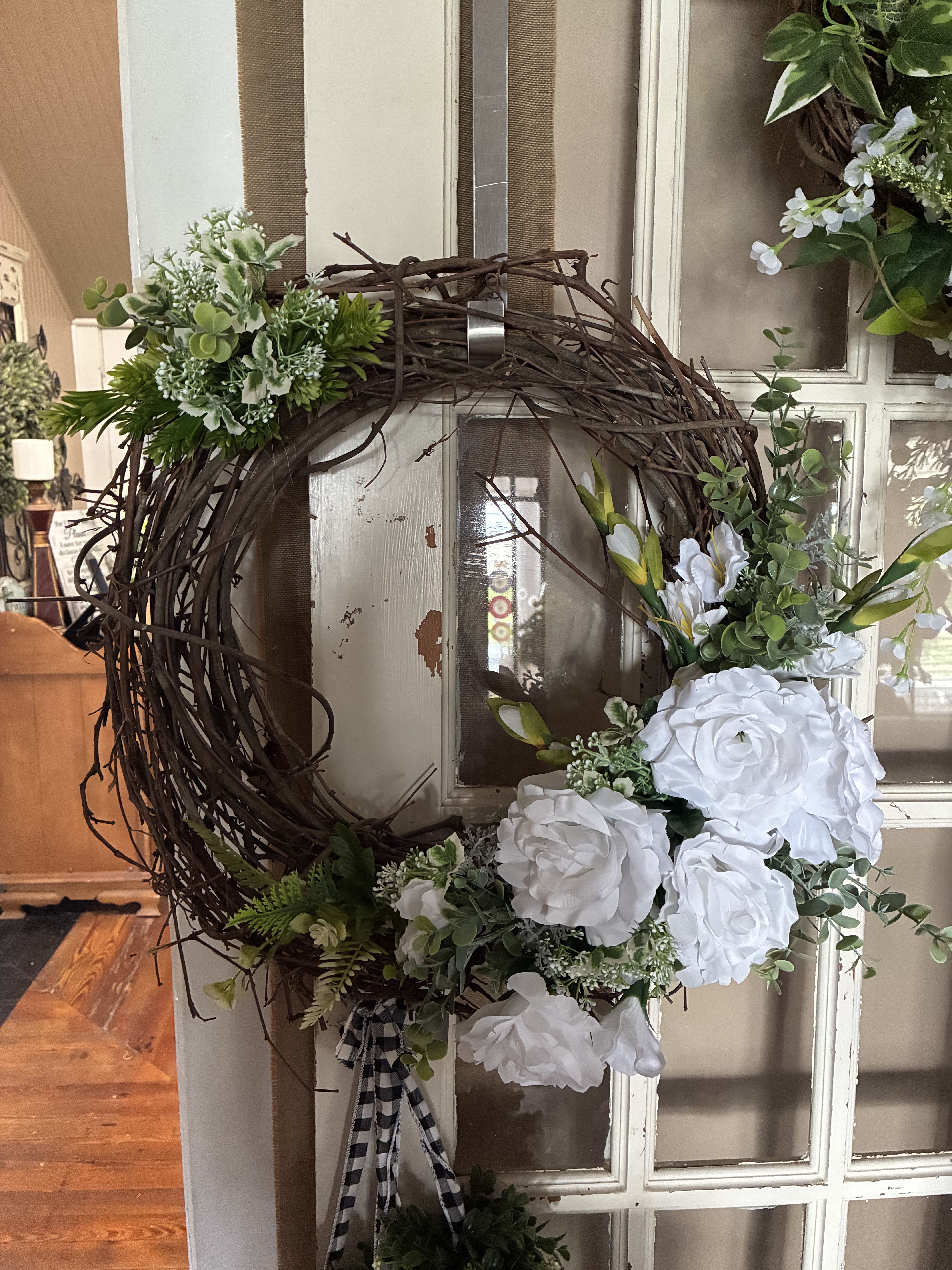 Spring Garden Silk Grapevine Wreath - A Grapevine Wreath in a circle of love, white lilies and greens. This wreath brings a bright, son shine  feel to your home.  Beautiful Grapevine wreaths are a stunning addition to any home. Hand made grapevine wreaths with high quality silk flowers. We create these wreaths in many different color schemes and price ranges. Perfect to send as sympathy gifts so that family can keep for years to come. Just pick your price and indicate what colors you prefer, we will create one Especially for you. Our stock changes frequently, so please call us @ 931-684-6863, if you have questions.  