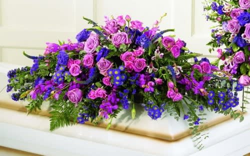 Large purple and pink floral arrangement on a casket