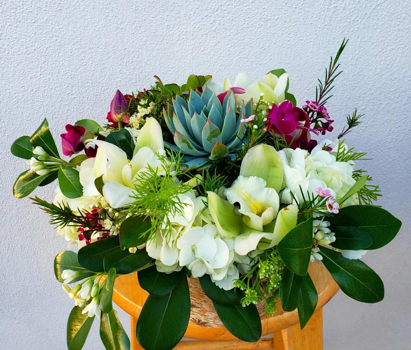 Mixed bouquet with white orchids, hydrangeas, and a blue succulent centerpiece