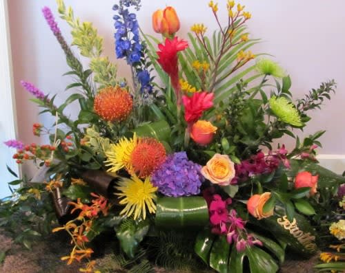 Large colorful floral arrangement with mixed blooms and tropical foliage