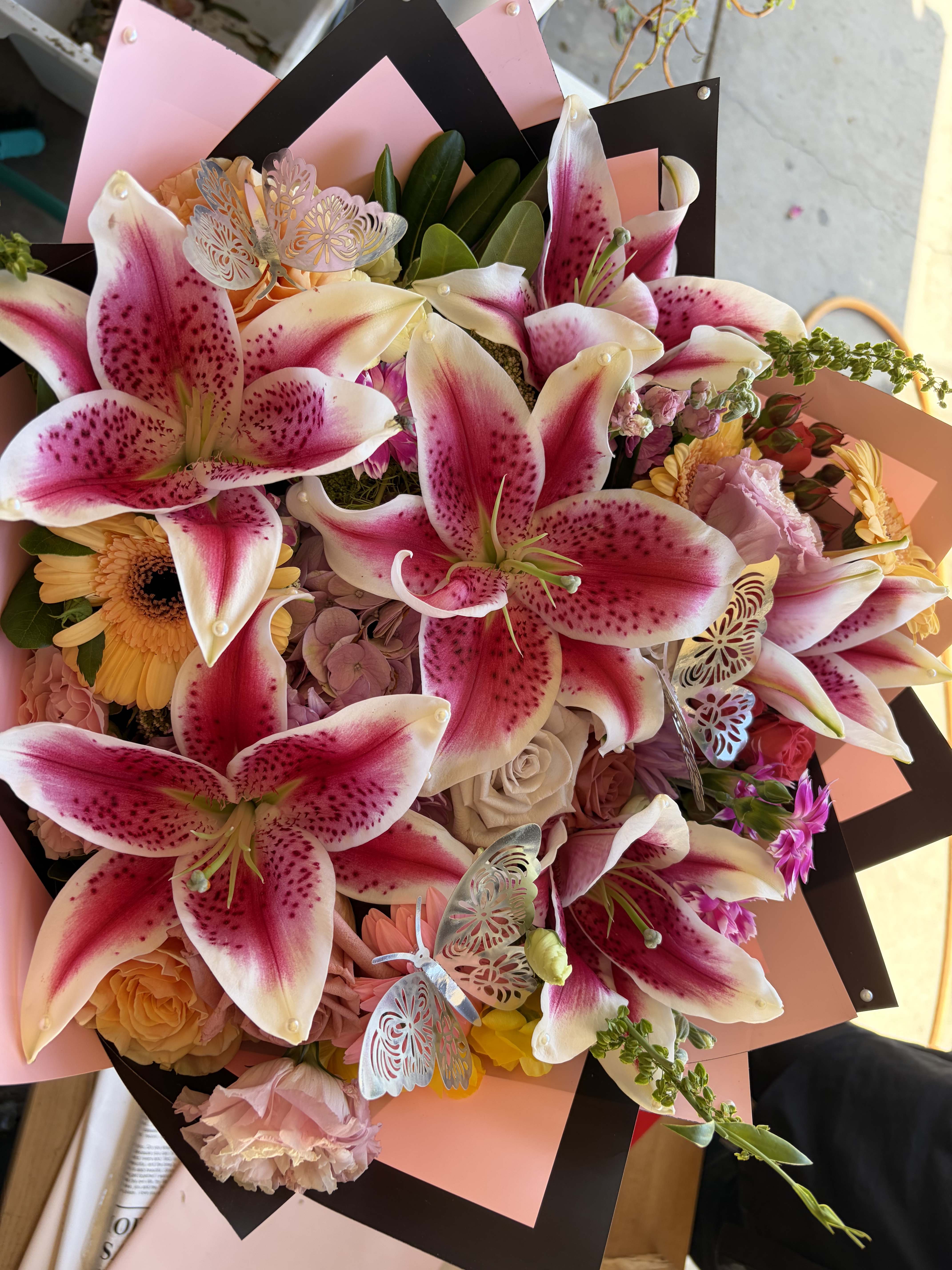 Bouquet of pink stargazer lilies, roses, and gerbera daisies with butterfly picks