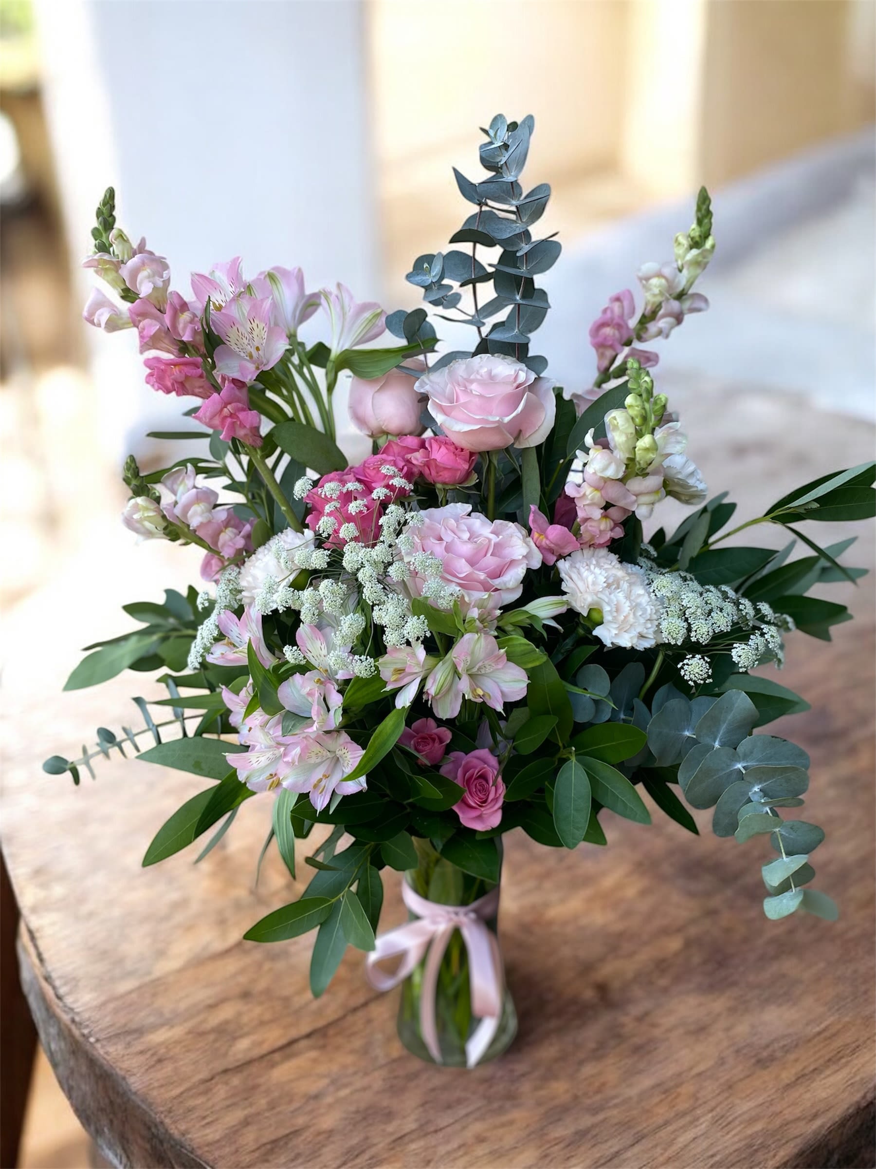 Pink and white bouquet in a clear glass vase with eucalyptus