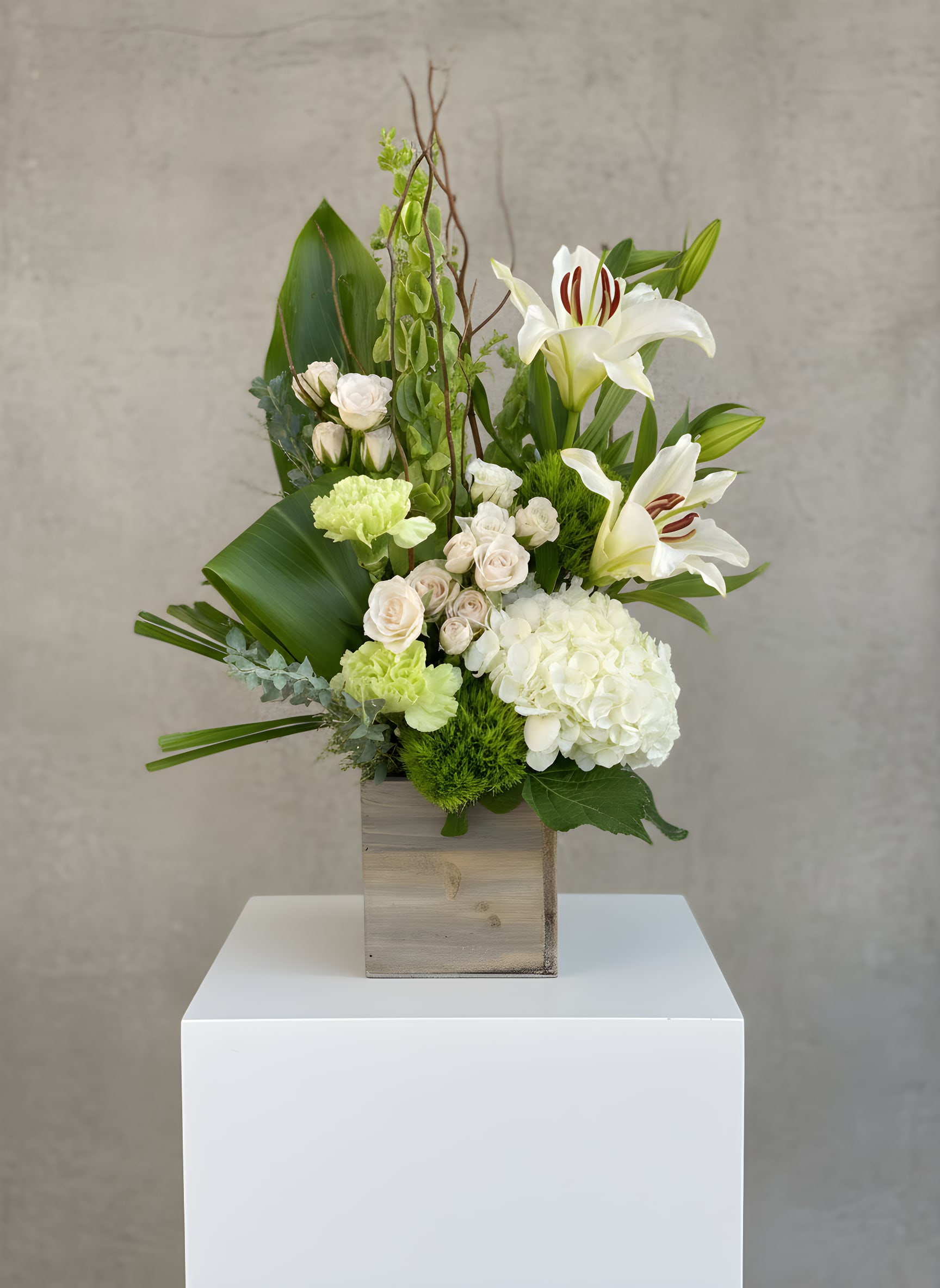 White lilies and pale roses in a wooden box arrangement