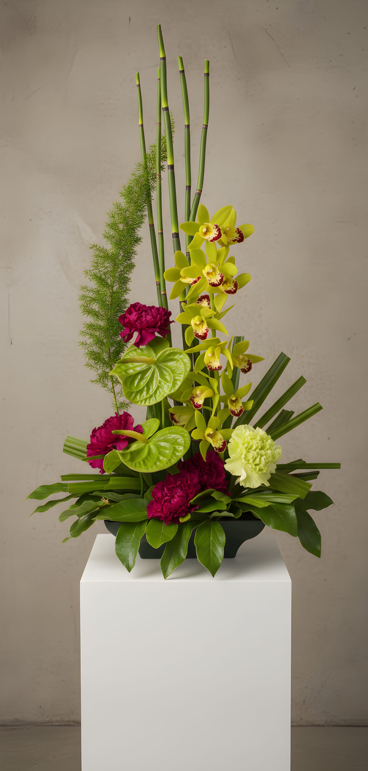 Tall floral arrangement with yellow orchids and magenta carnations in a black container
