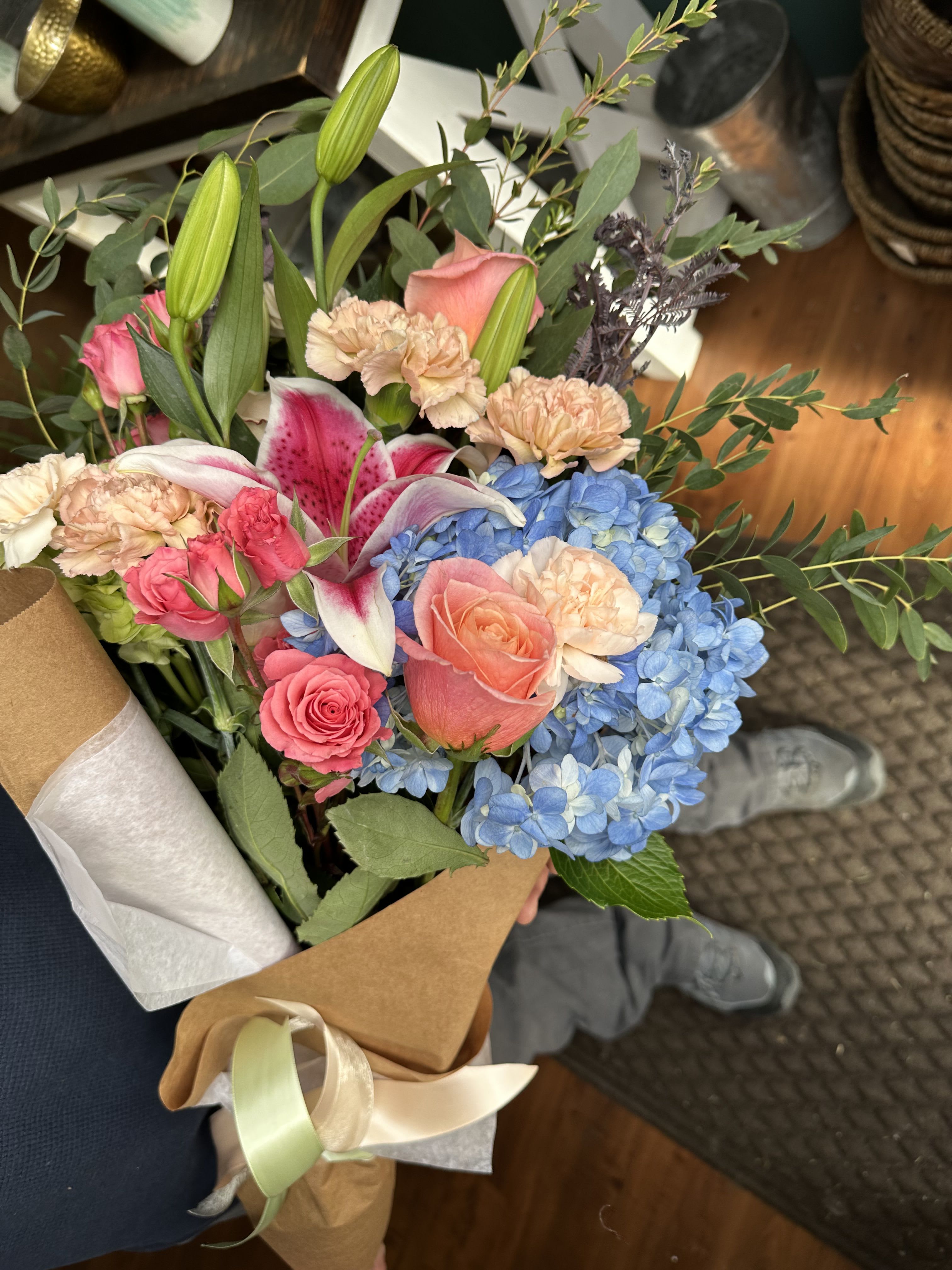 Hand-tied bouquet with pink roses, blue hydrangeas, lilies, and carnations