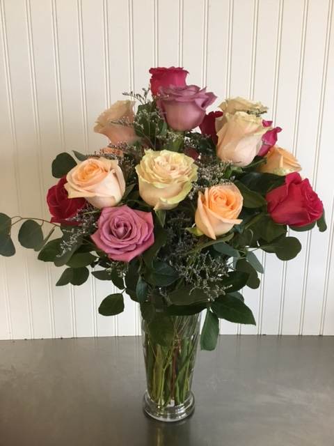 Mixed roses in a clear glass vase with greenery