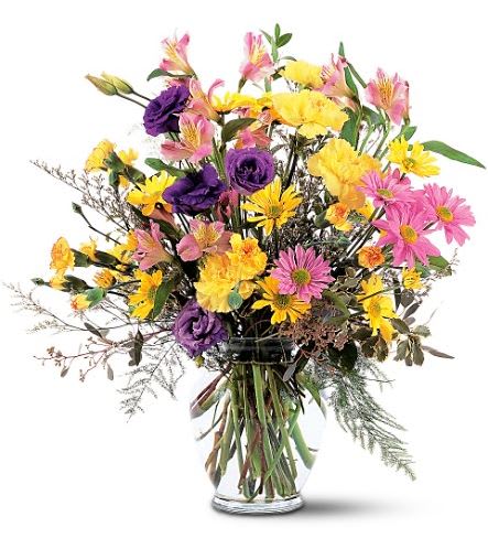 Mixed bouquet of yellow, pink, and purple flowers in a clear glass vase
