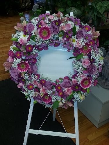 Heart-shaped floral wreath on a standing easel with pink and purple flowers
