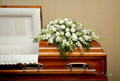 All White Casket Spray by Joni - Show purity of love with a mix of all-white flowers that’s as gentle and pure as a cloud. Accented with a mix of greenery, fragrant white flowers create a lovely and traditional casket spray.