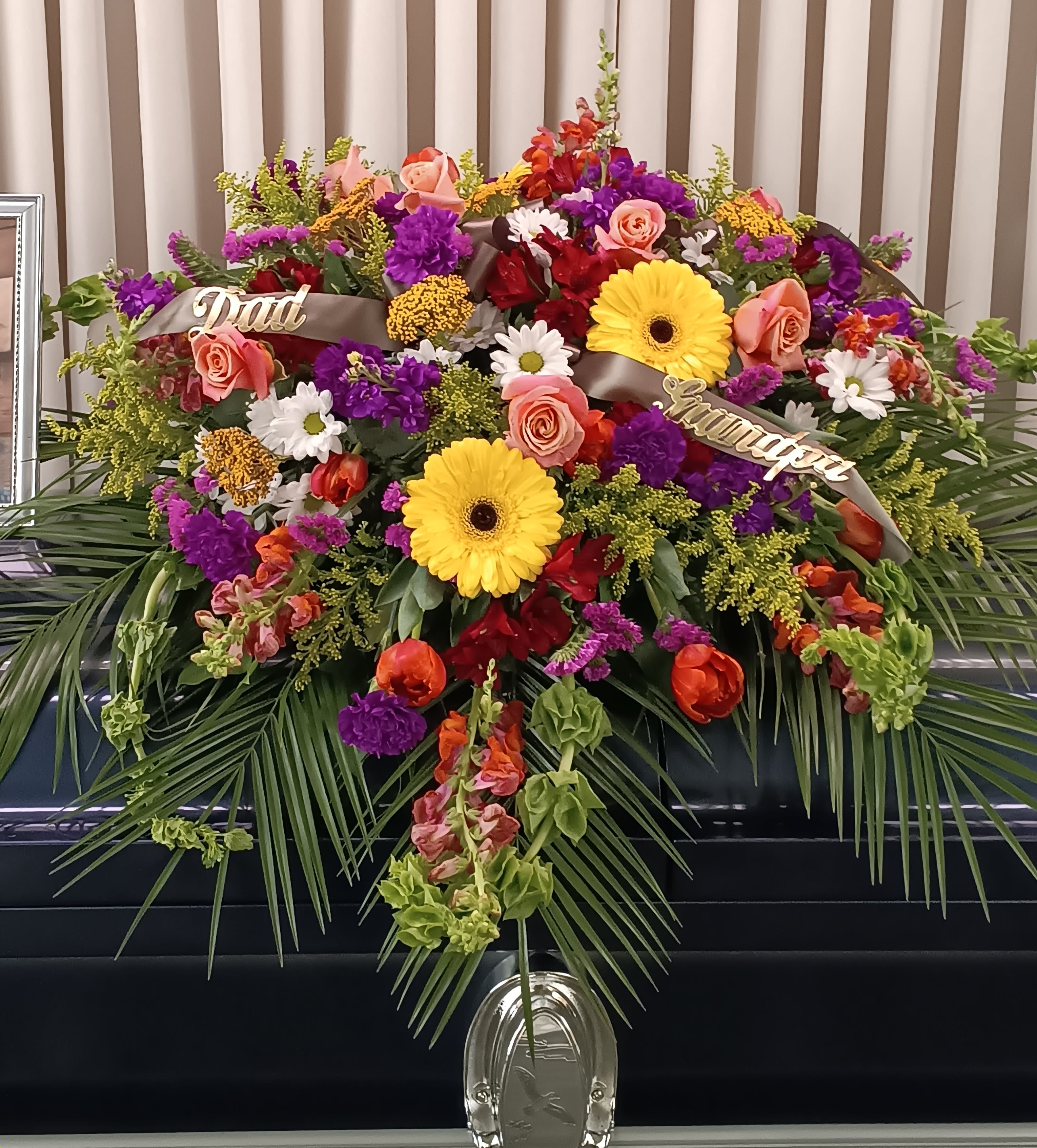 Large funeral spray with mixed flowers and ribbons on a stand