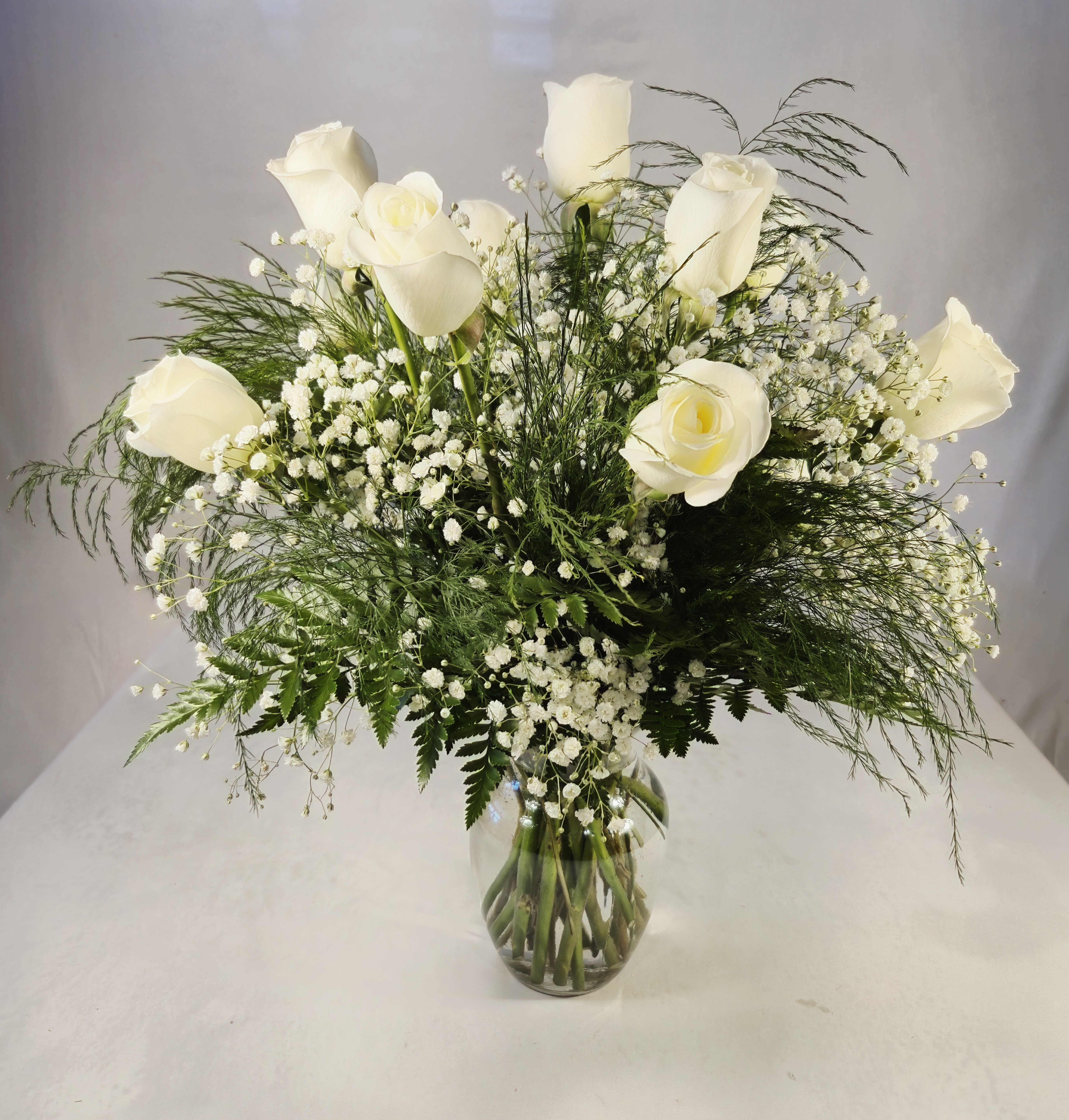 White roses arranged in a clear glass vase with airy filler flowers