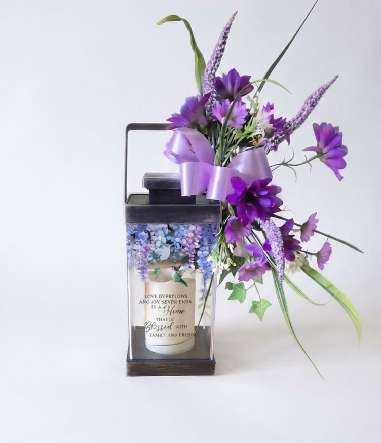 Purple floral arrangement in a lantern-style candle holder