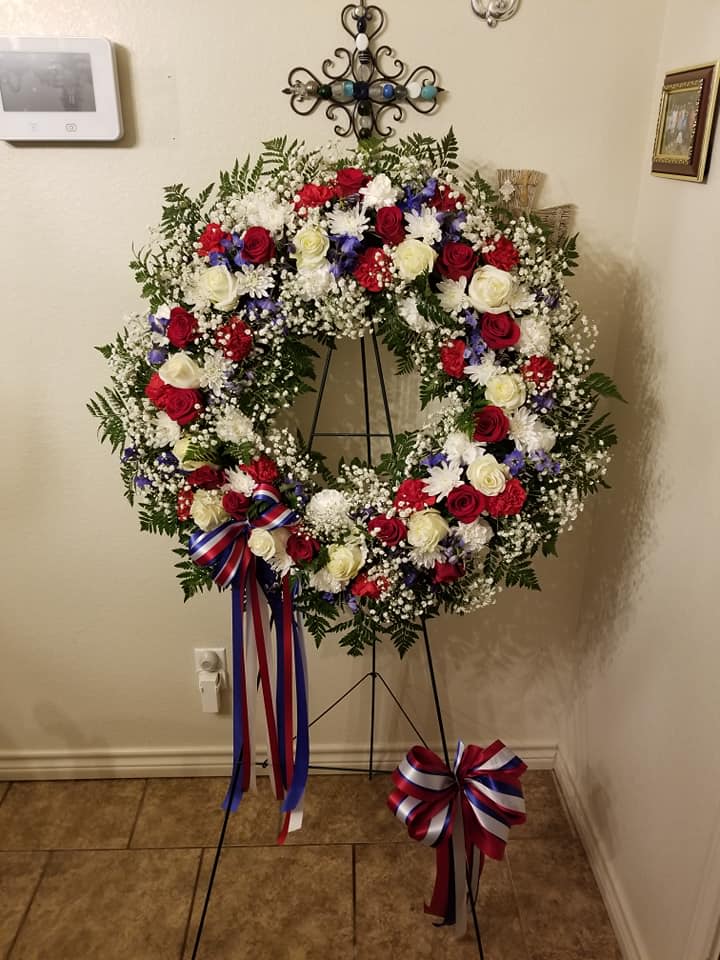 Large patriotic funeral wreath with red, white, and blue flowers on a stand
