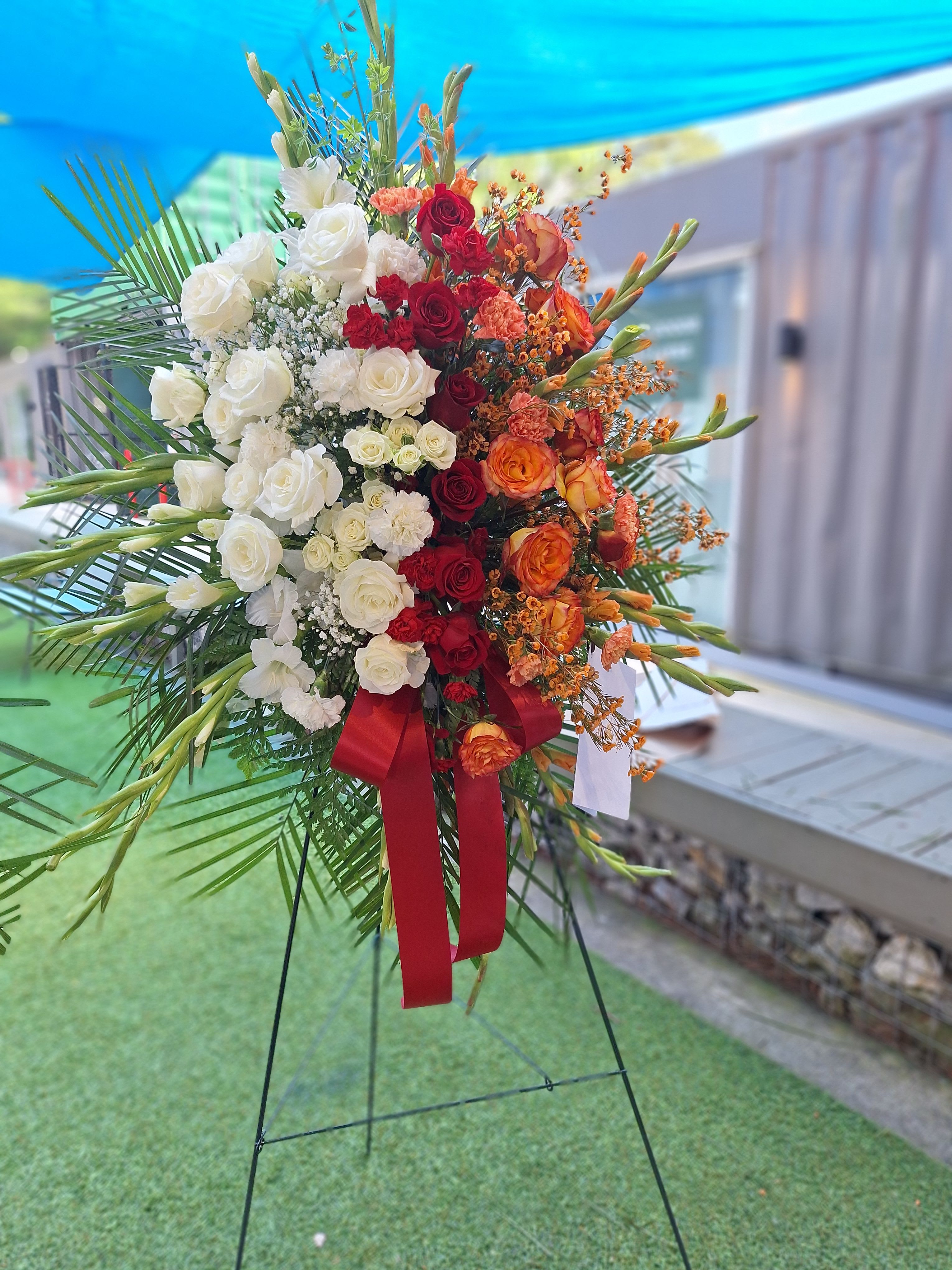 Large standing floral spray with white, red, and orange roses
