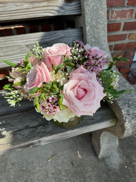 Pink roses arranged in a low glass vase with small filler flowers