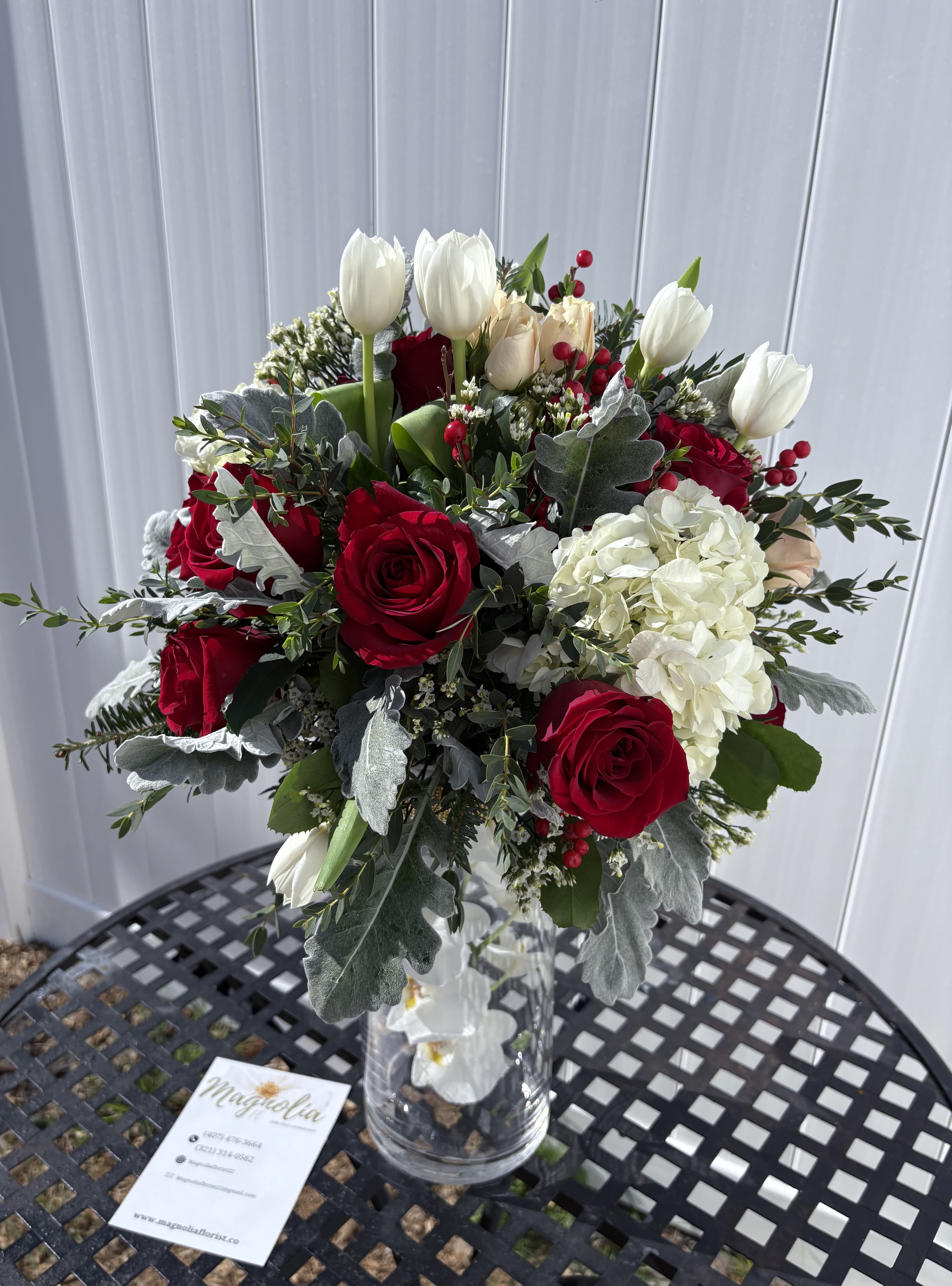 Bouquet of red roses and white tulips in a clear glass vase