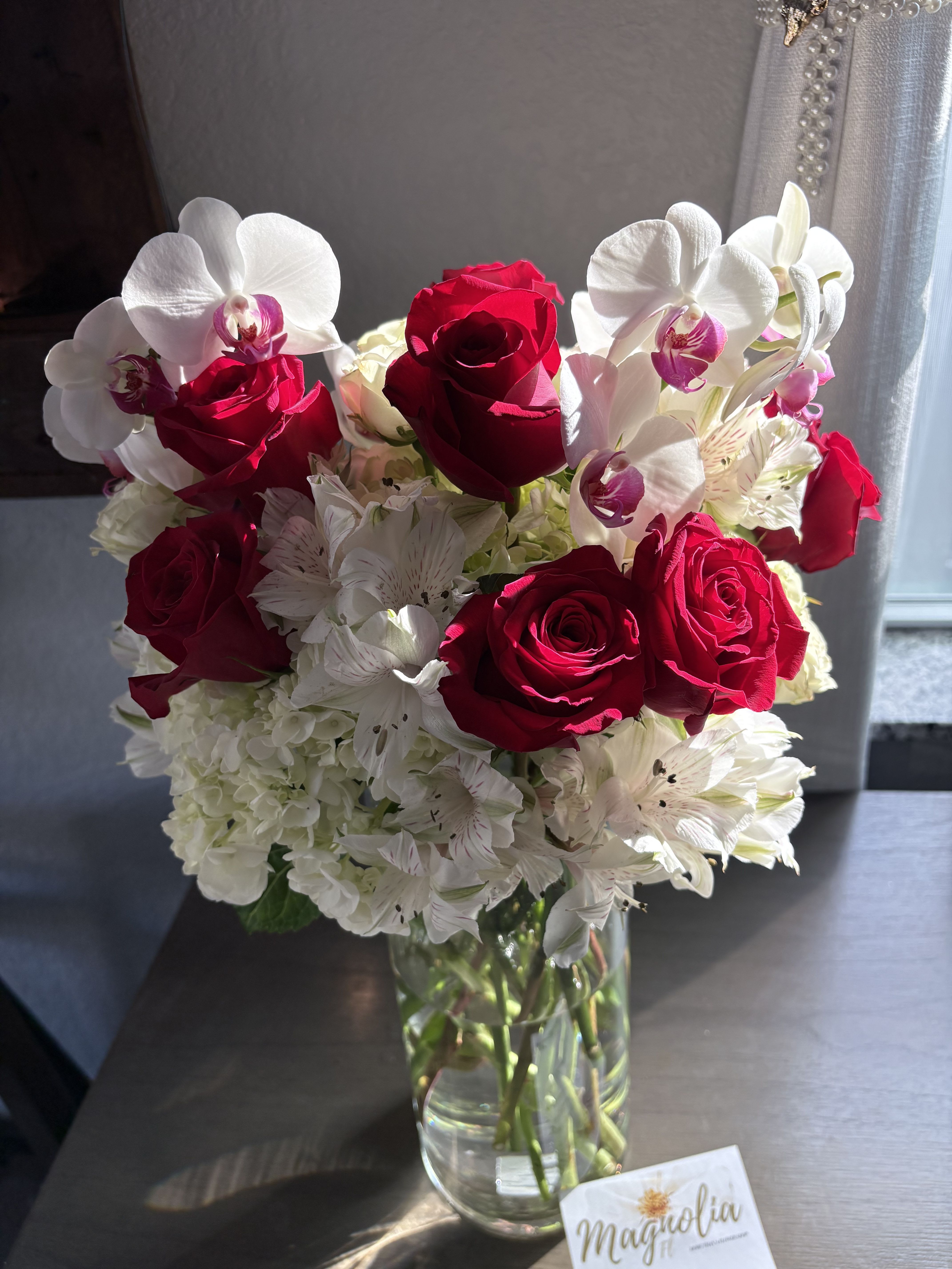 Red roses and white orchids in a clear glass vase