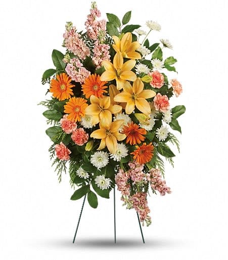 Standing floral spray with yellow lilies, orange daisies, and pink flowers