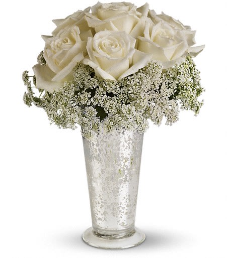 White roses in a tall silver vase with baby's breath