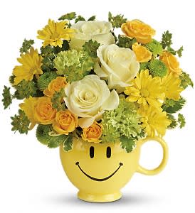 Yellow smiley-face mug holding white and yellow flowers