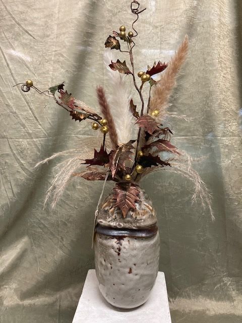Tall dried floral arrangement in a ceramic vase with feathery plumes and gold accents
