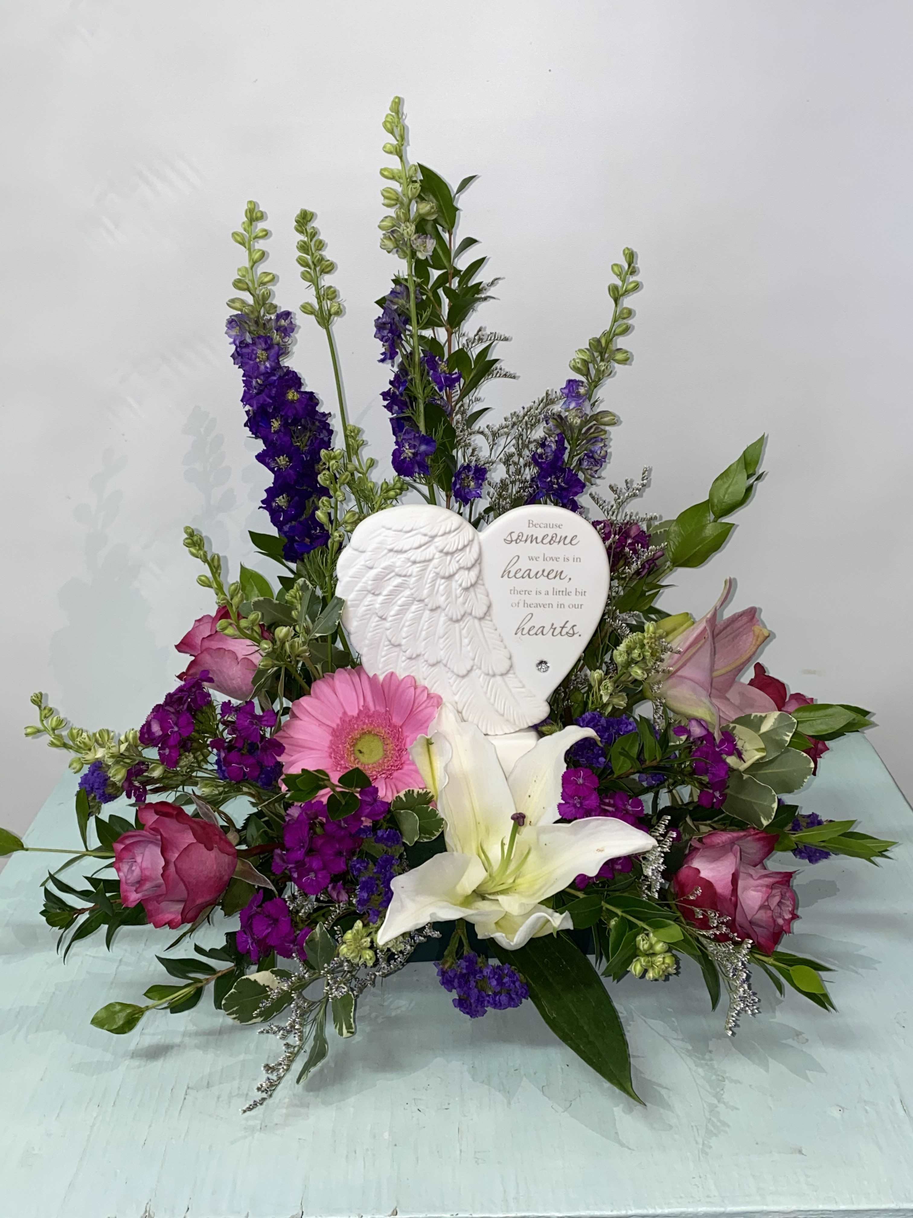 Sympathy floral arrangement with pink and purple flowers and an angel memorial plaque