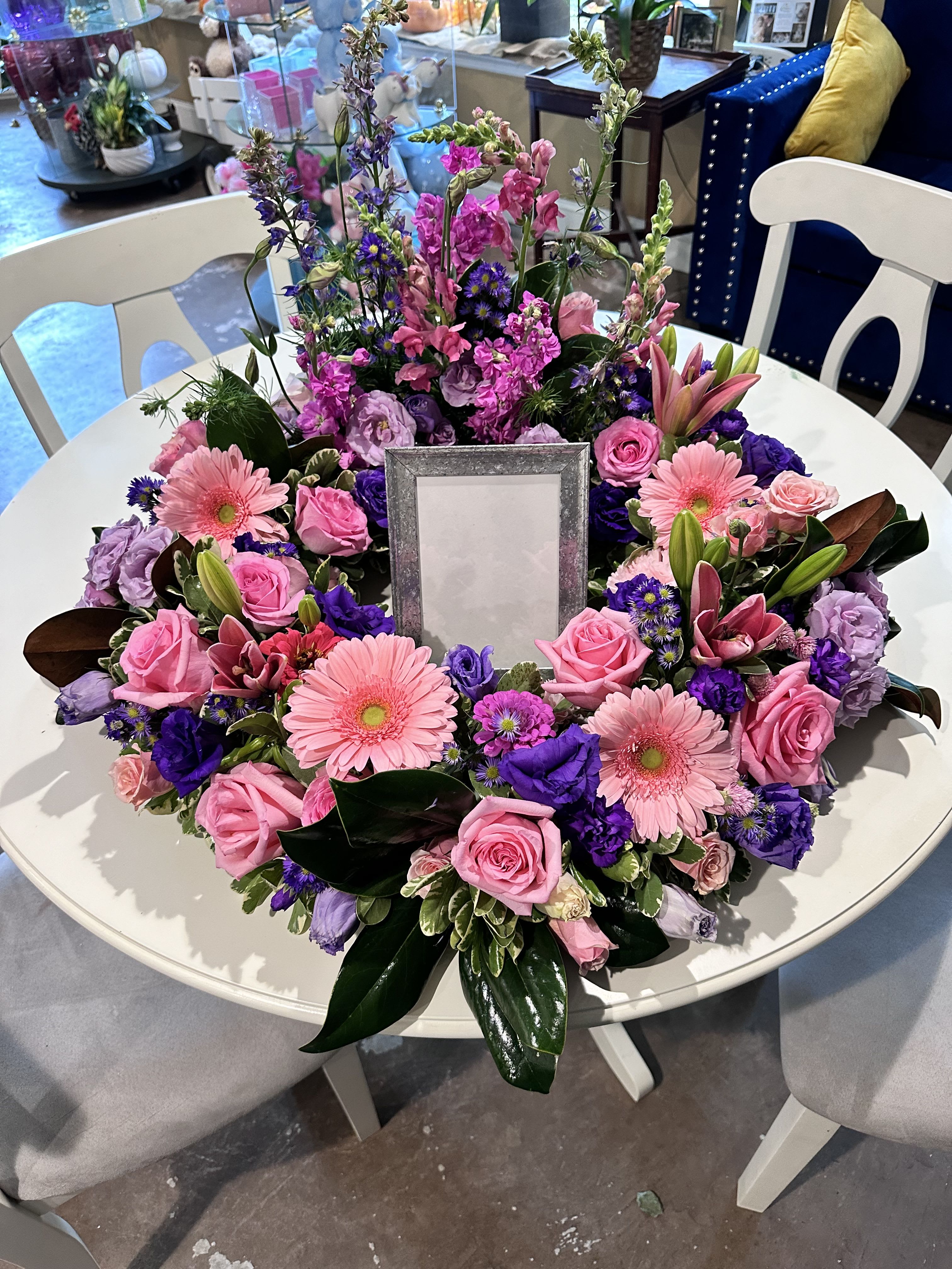 Round floral wreath with pink and purple blooms around a center frame