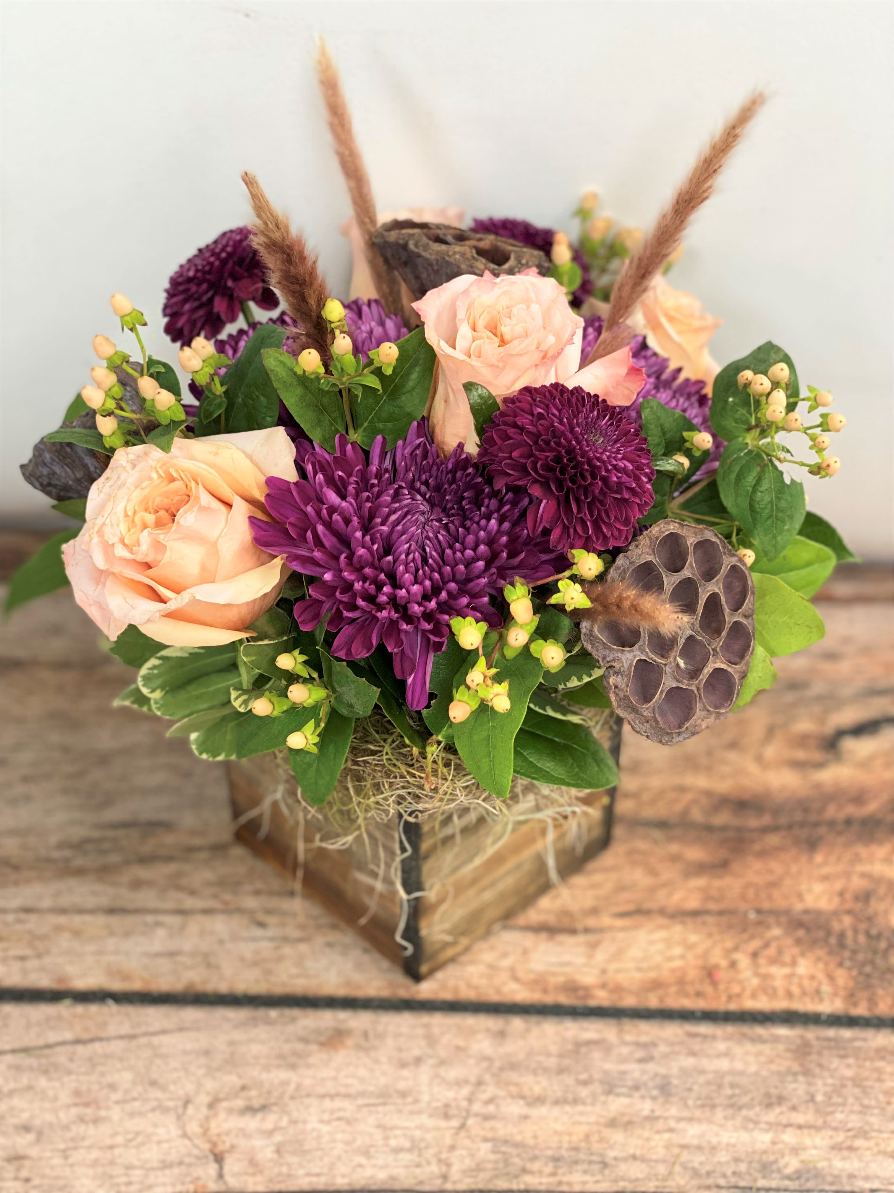 Peach roses and purple chrysanthemums in a wooden box with dried pods