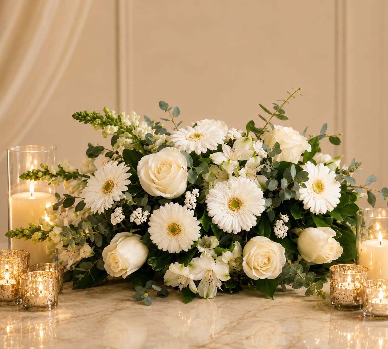 Grace Centerpiece - Soft, soothing, and beautifully composed, this all- white arrangement offers a gentle expression of peace and comfort. Elegant white roses, gerbera daisies, and delicate mums are arranged in a graceful elongated style, surrounded by lush greenery eucalyptus for a touch of natural refinement.  