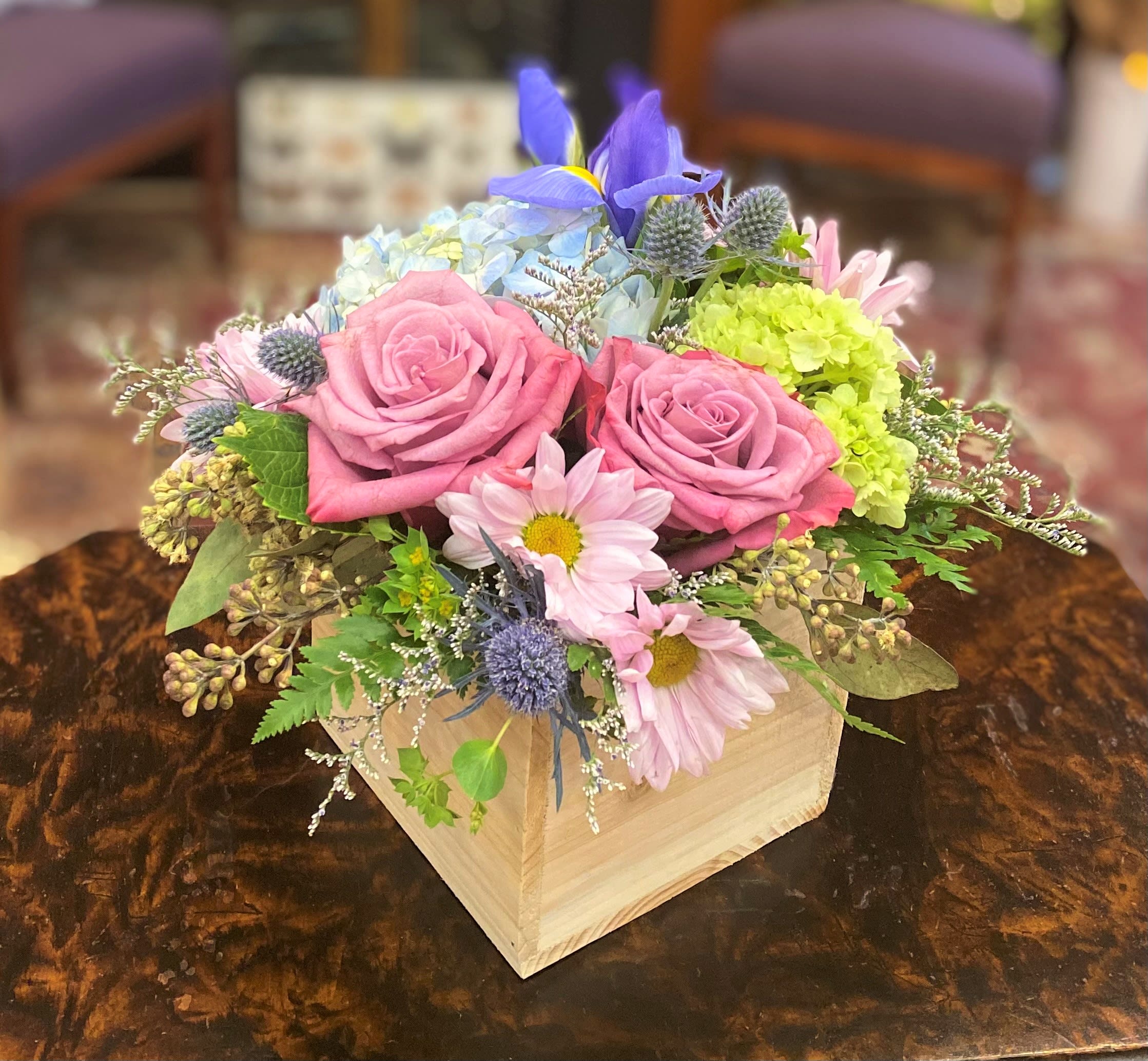 Pink roses and pastel mixed flowers arranged in a wooden box