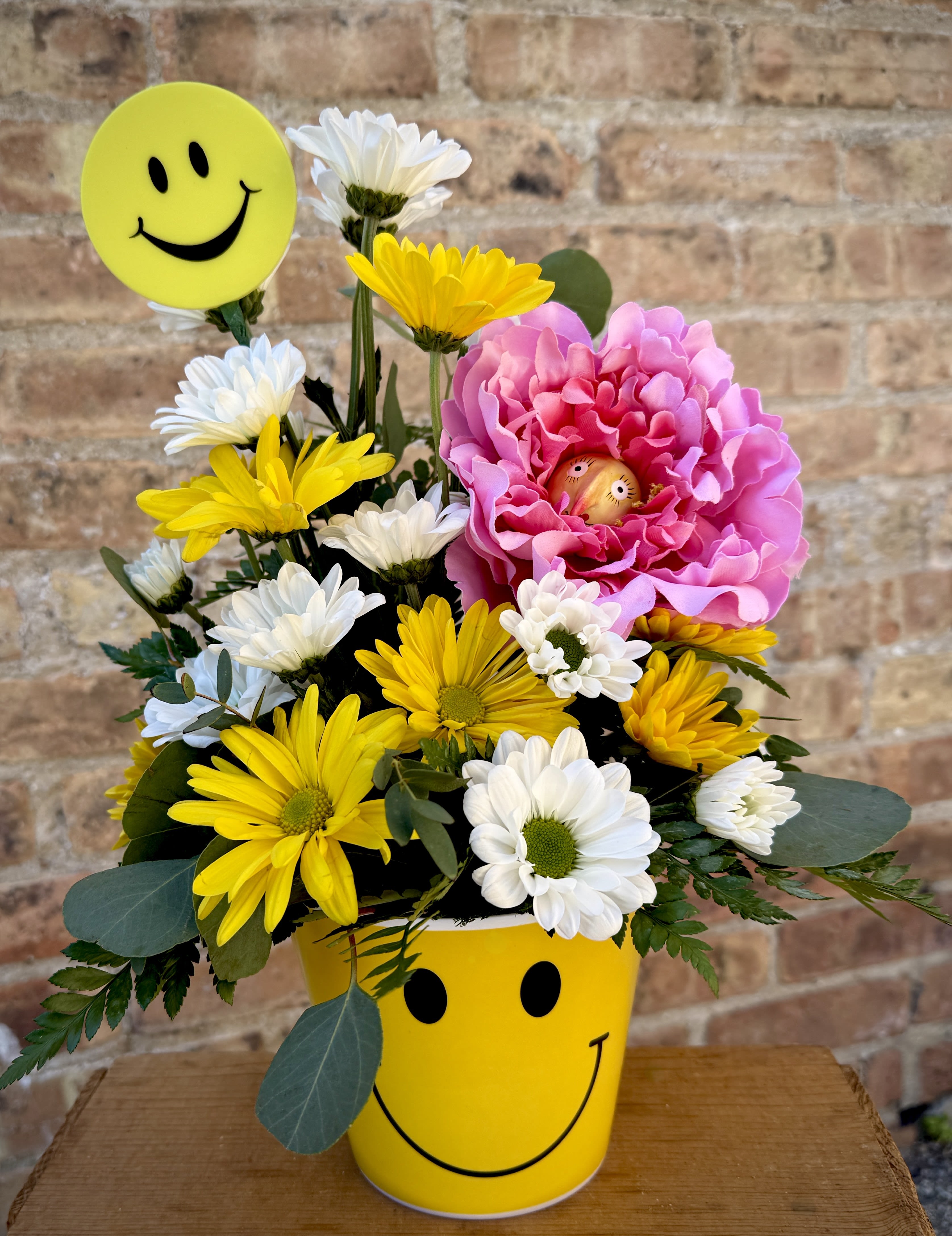 Happy Days - Who can help but smile back at this adorable arrangement? It makes you smile if you're feeling down. It sends your smile across the miles. A keepsake smiley face daisy!  We are proud to deliver our flower creations to the Kenosha, Somers, and Pleasant Prairie area. With over 55 years of combined flower design experience in Kenosha, Wisconsin, A Summer's Garden Florist and Gifts is the perfect choice for the freshest flowers, most creative designs, and exceptional customer service.