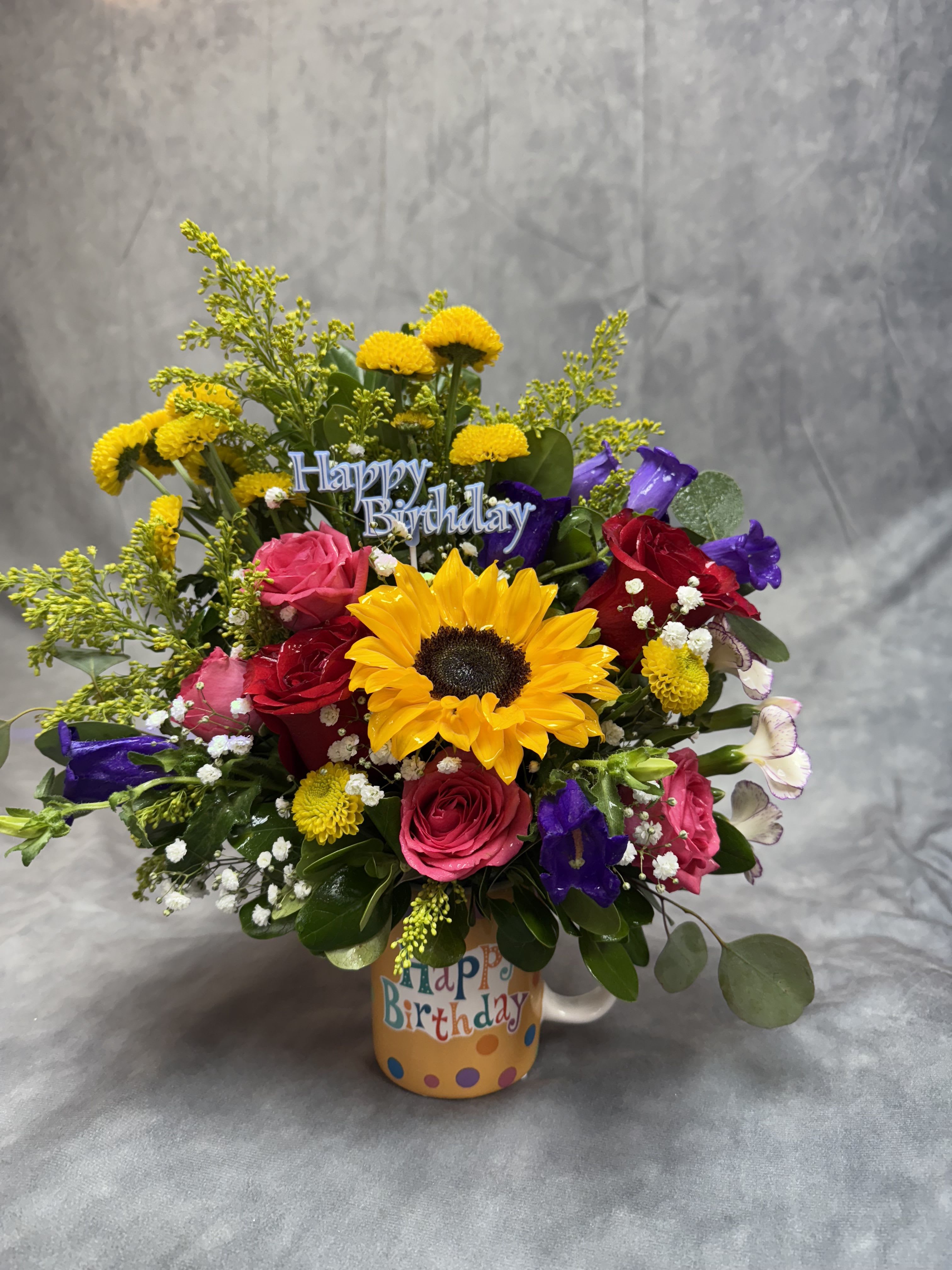 Colorful birthday bouquet in a mug with roses and a sunflower