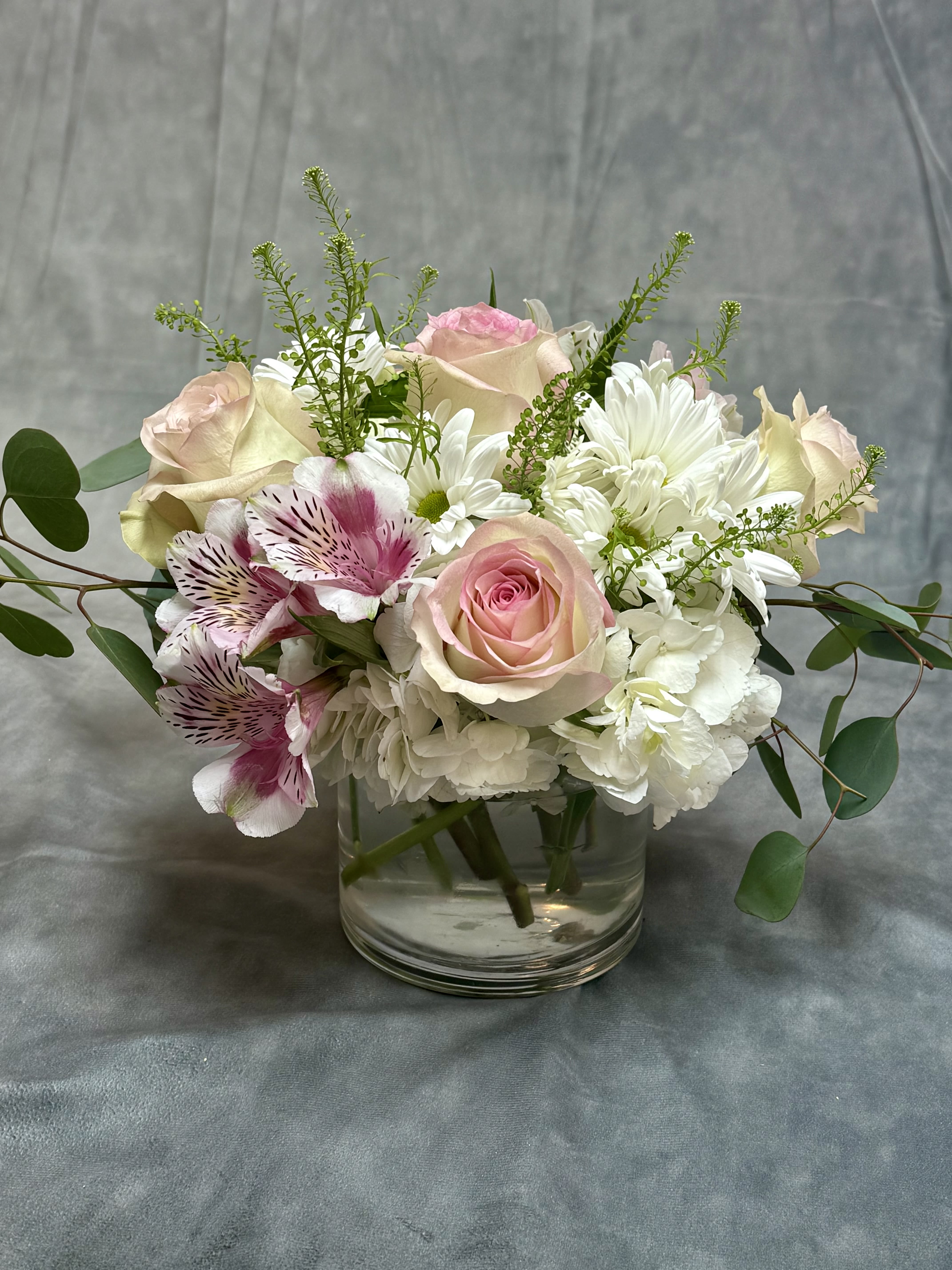 Pink and white roses with alstroemeria in a clear glass vase