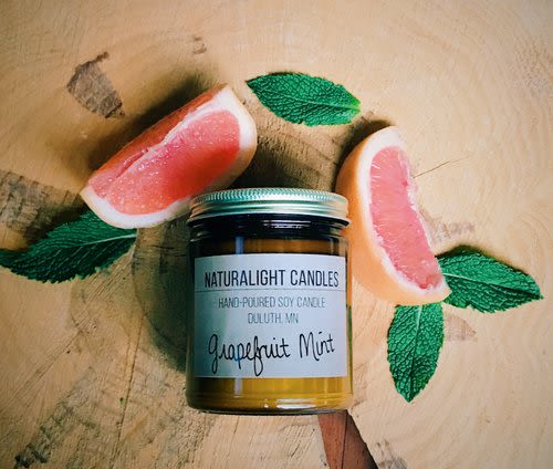 Jar candle with grapefruit slices and mint leaves on a wooden surface