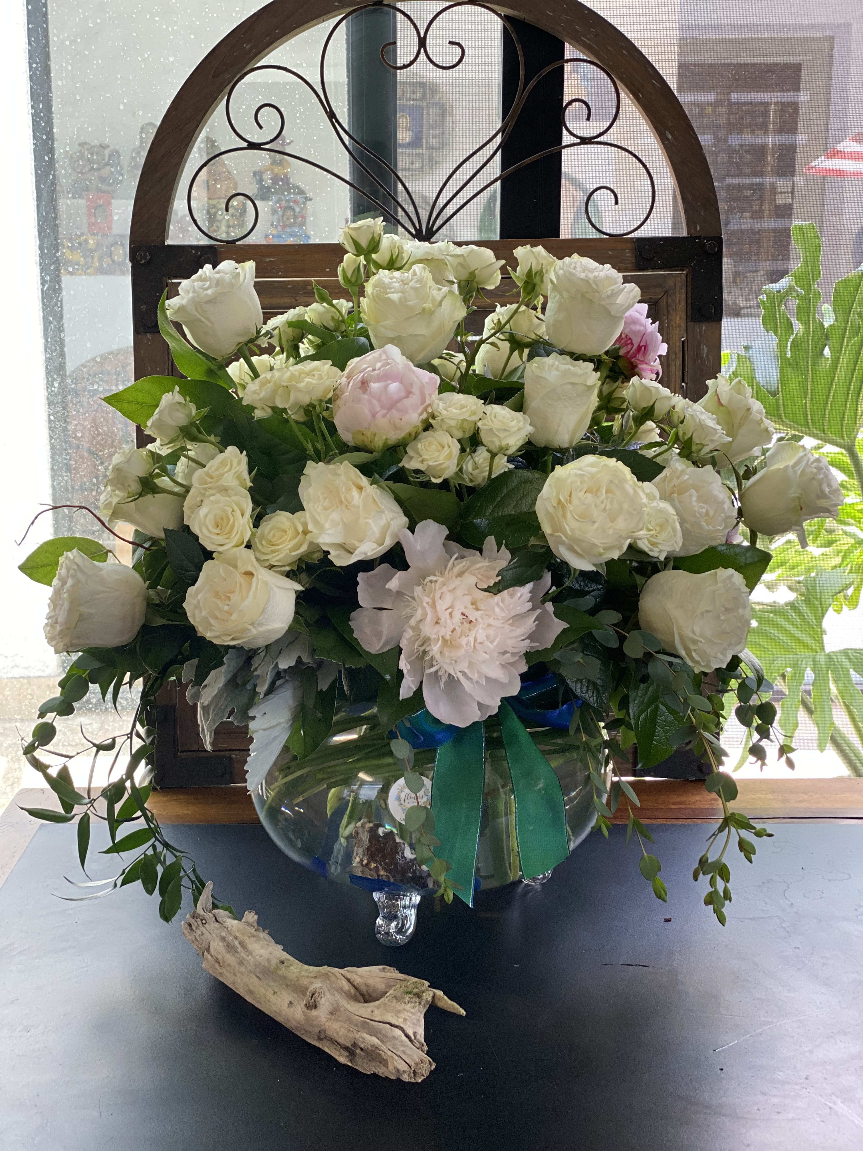 White rose arrangement in a glass vase with pink blooms and greenery