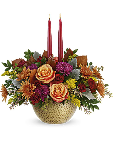 Autumn floral arrangement with two red taper candles in a gold bowl