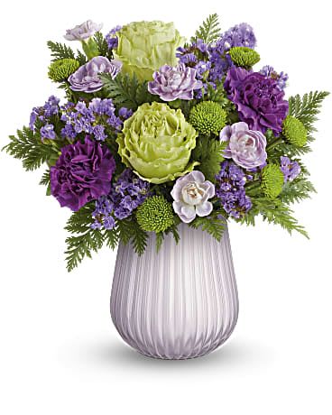 Purple and green floral arrangement in a ribbed glass vase