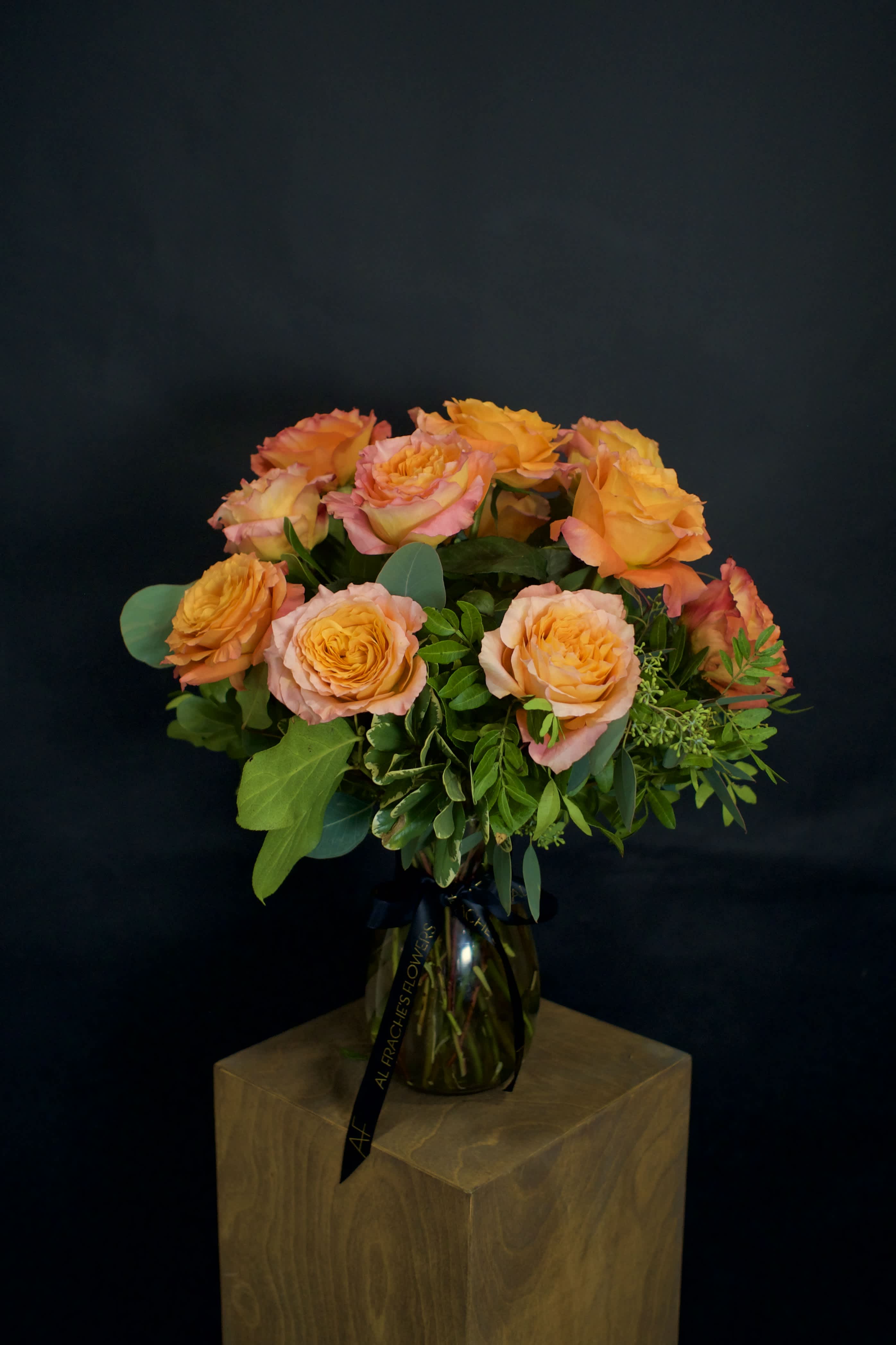 Orange and pink roses arranged in a glass vase