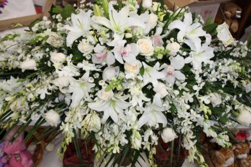 Large white floral spray with lilies, orchids, and roses