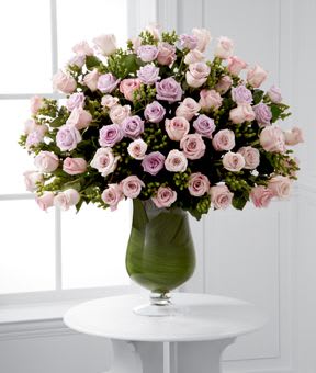 Pink and lavender roses arranged in a green glass vase