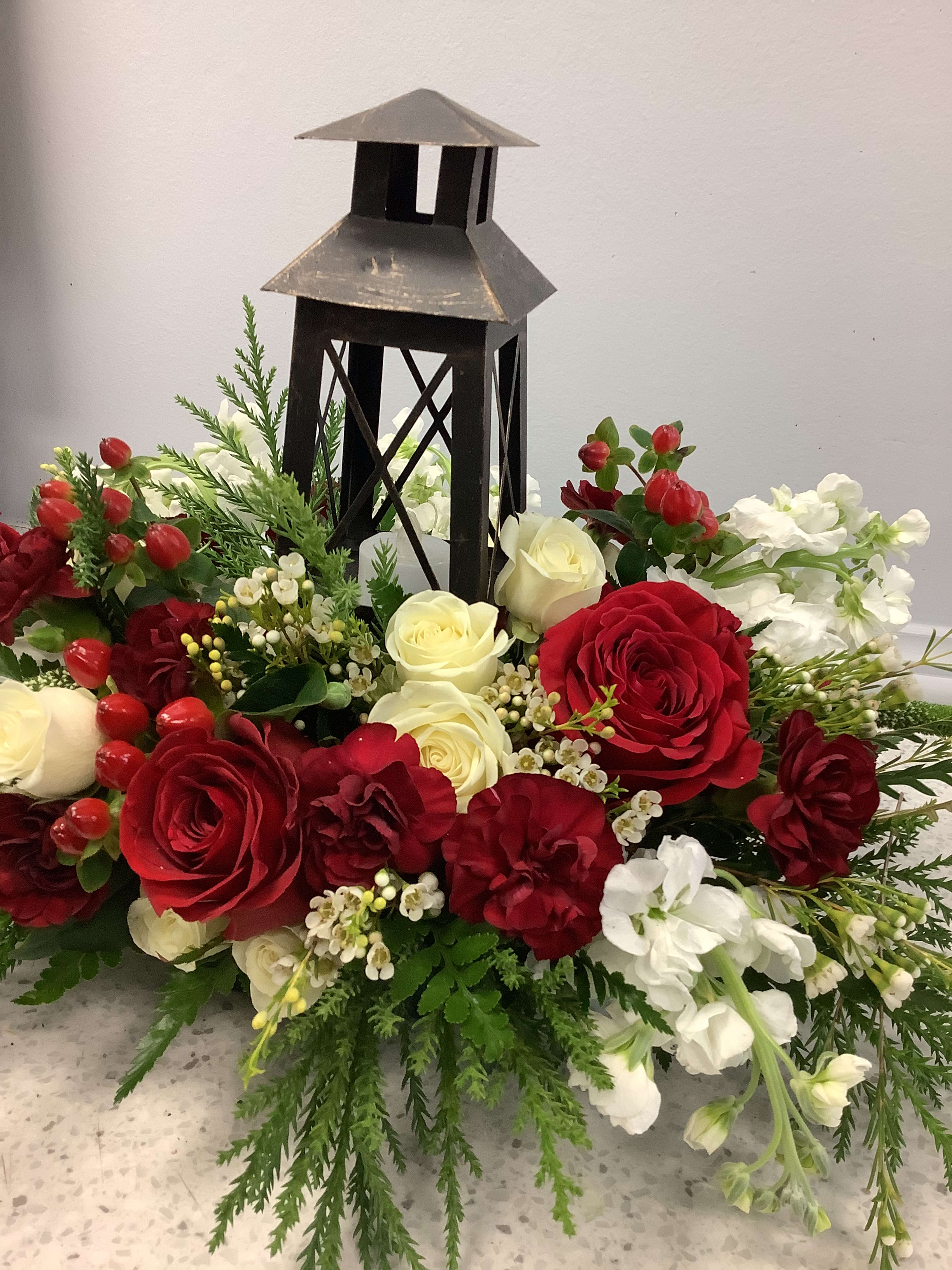 Red and white floral arrangement around a black lantern