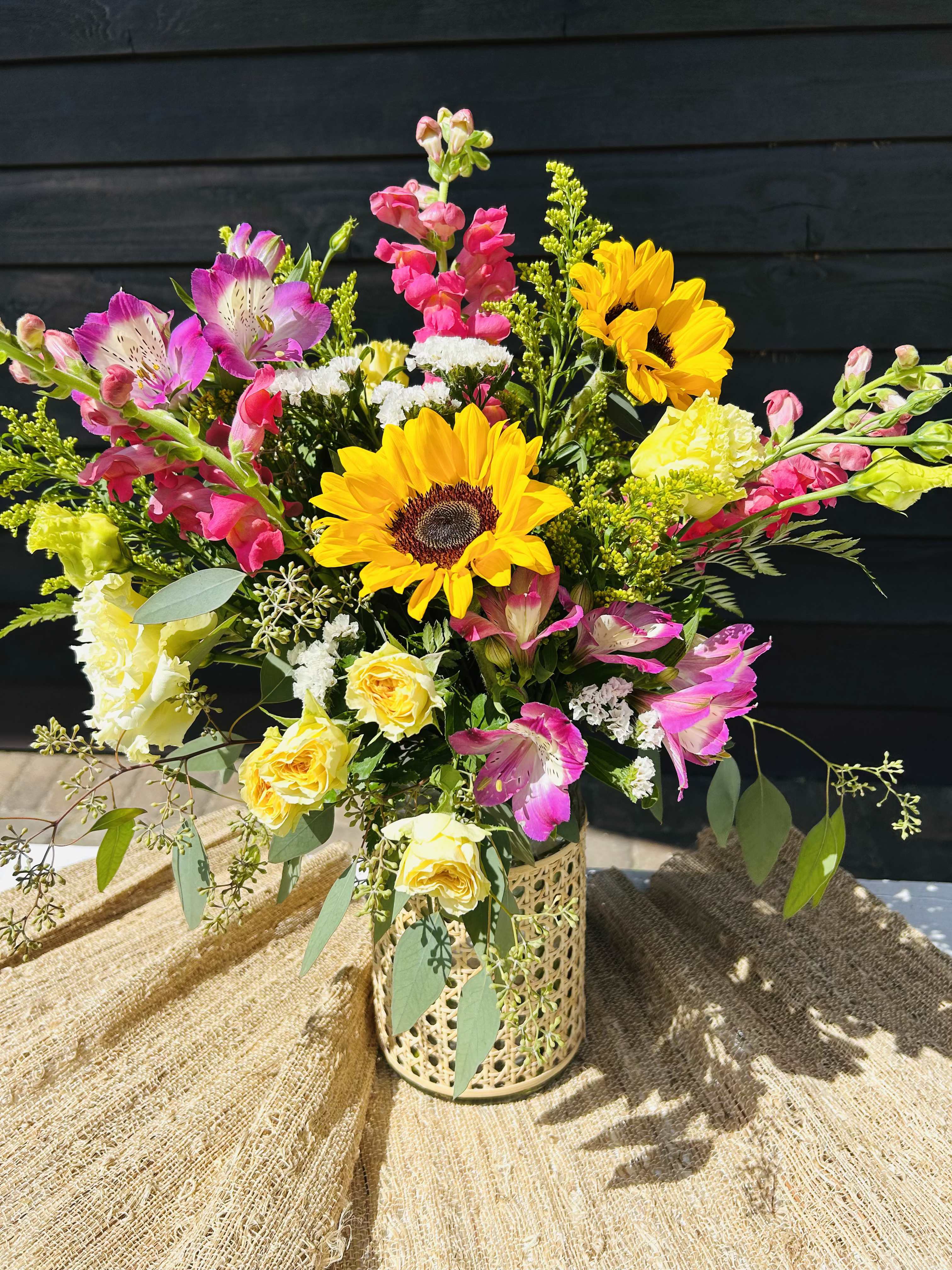 Mixed bouquet with sunflowers, pink alstroemeria, and yellow roses in a decorative vase