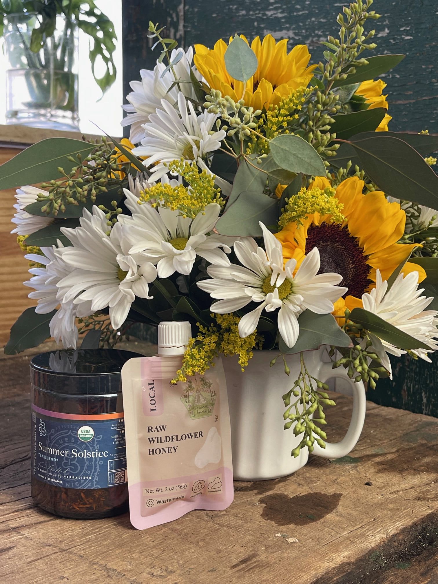 Sunflower and white daisy bouquet in a white mug with tea and honey gifts