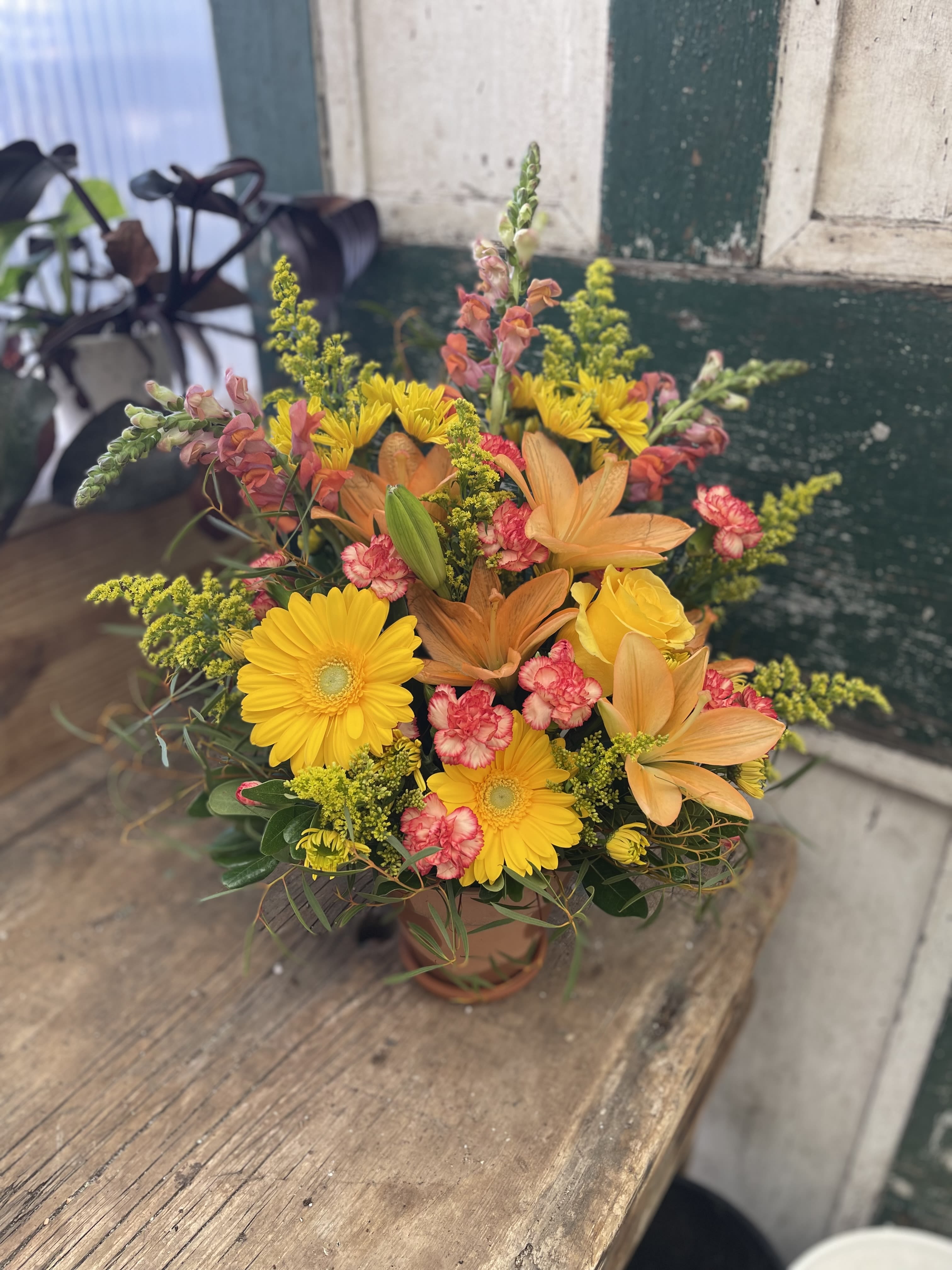 Mixed bouquet with yellow daisies, orange lilies, and pink carnations in a vase