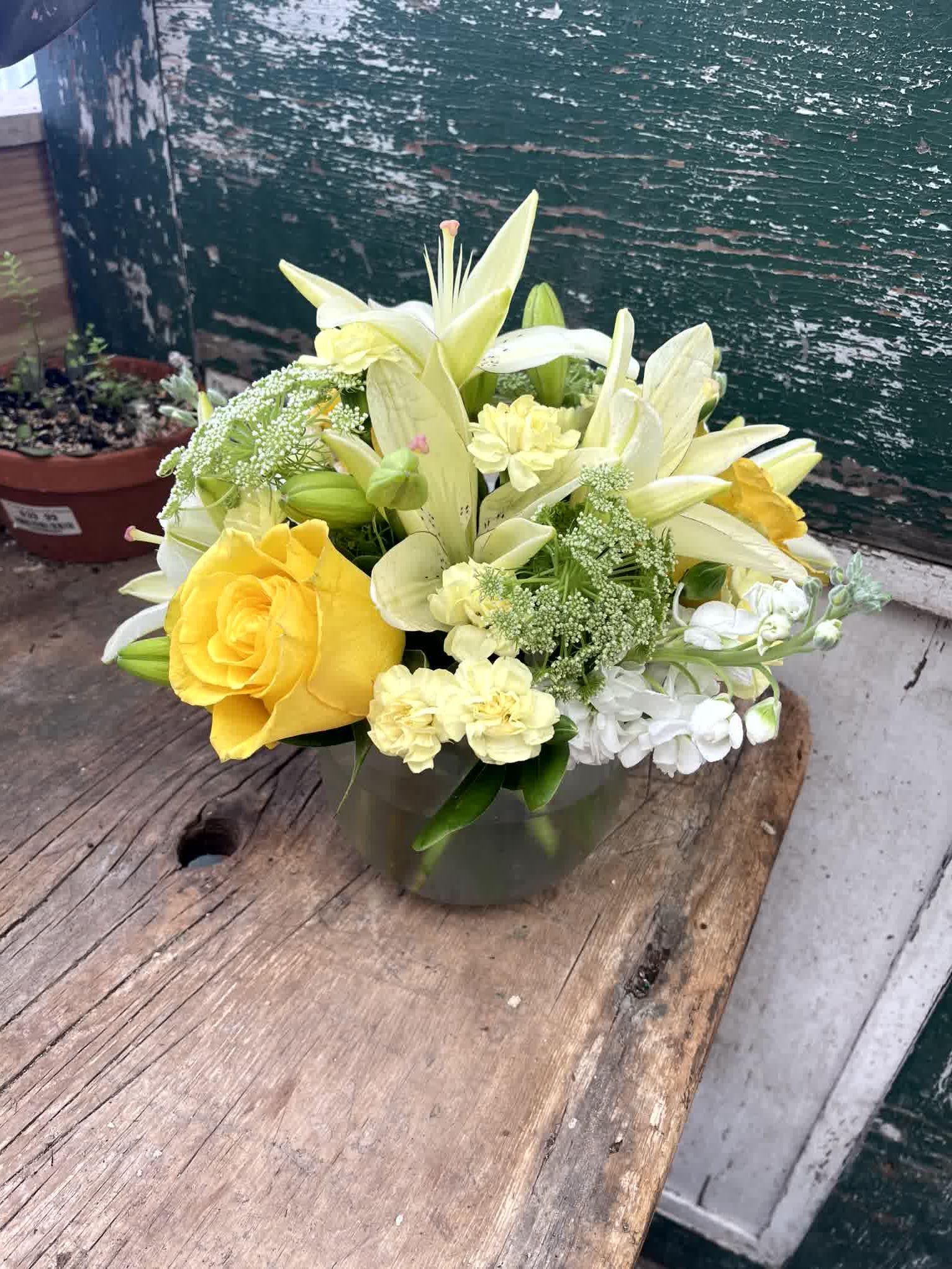 Yellow roses and white lilies arranged in a glass vase