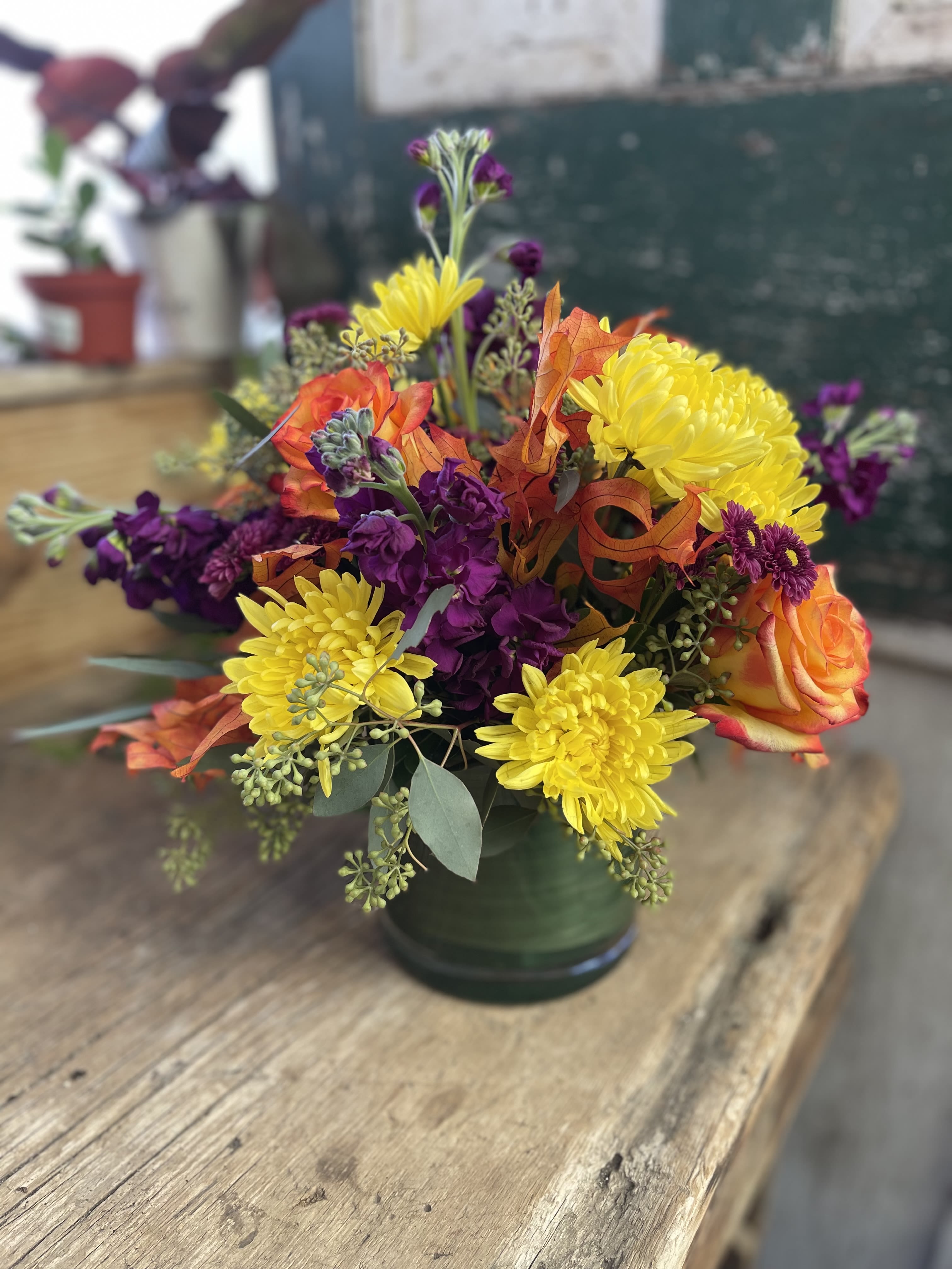 Bouquet of yellow chrysanthemums and orange roses in a green vase