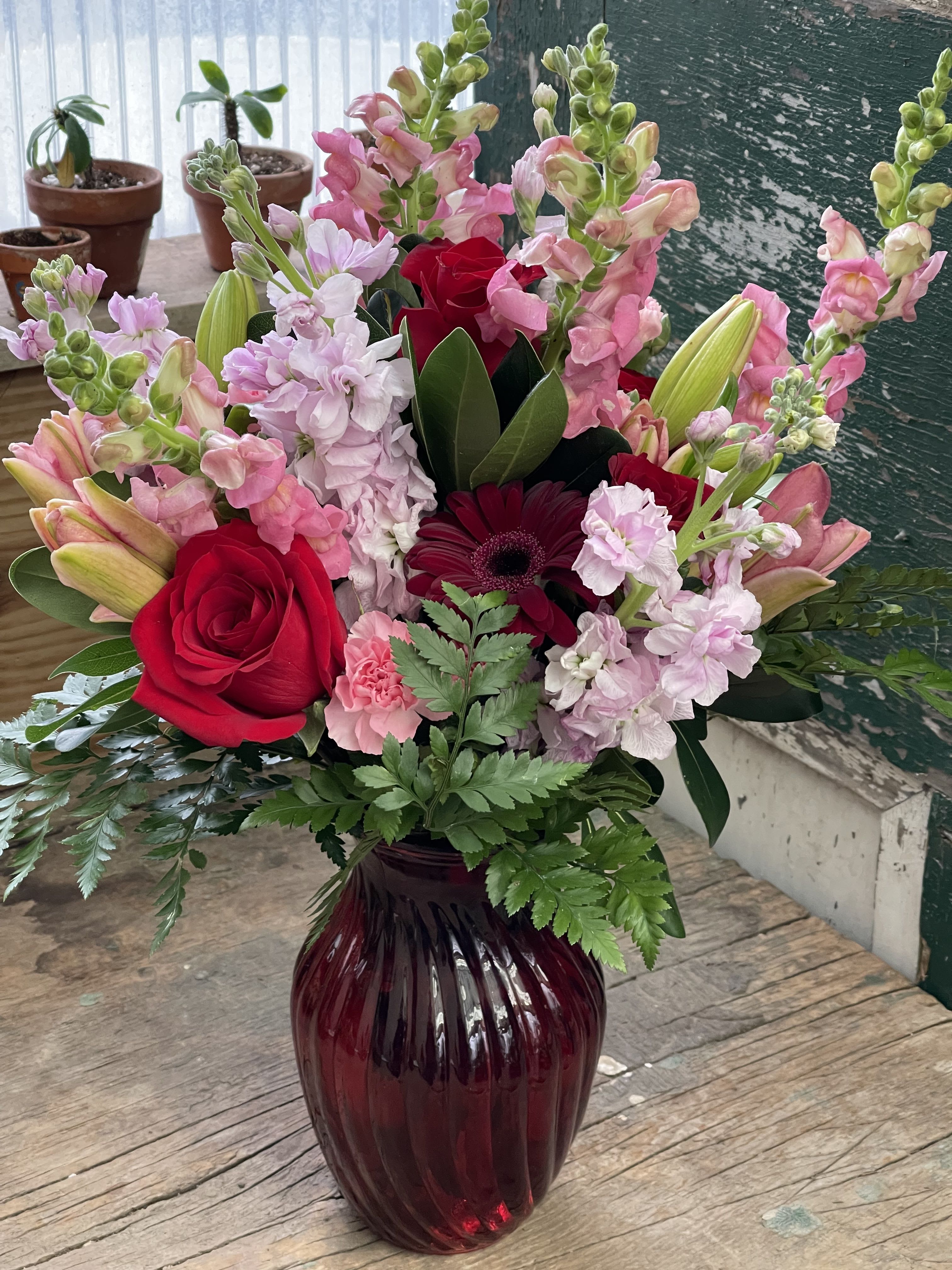 Mixed pink and red flower arrangement in a burgundy vase