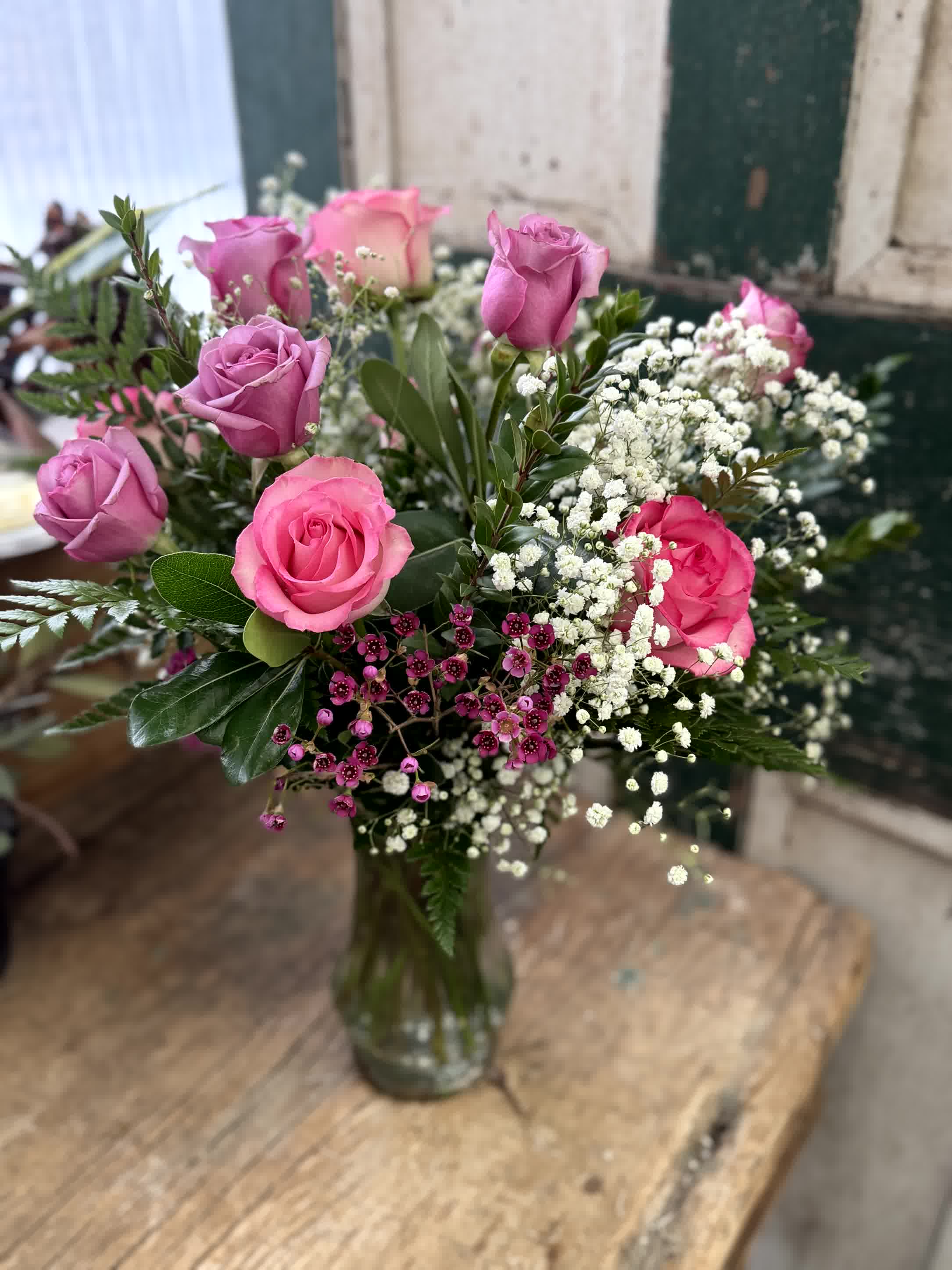 Pink and lavender roses arranged in a glass vase with white baby's breath