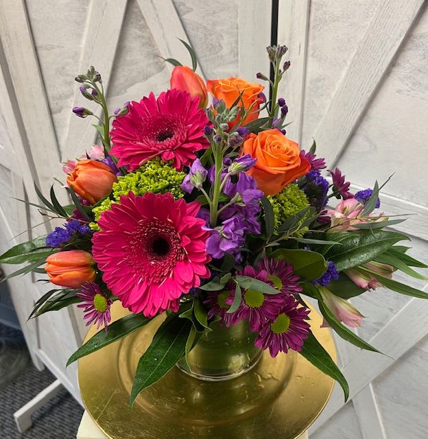 Bright mixed bouquet in a glass vase with pink gerberas and orange roses