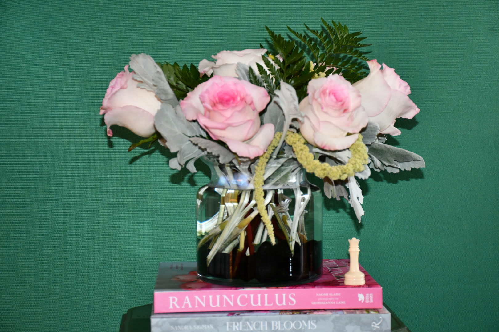 Pink and white roses in a glass vase with greenery